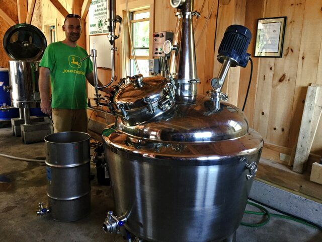 Blender Keith Van Sise with his still at Gristmill. The shiny, pot bellied equipment takes up one corner of the distillery’s new barn. (Credit: Kim Dedam)